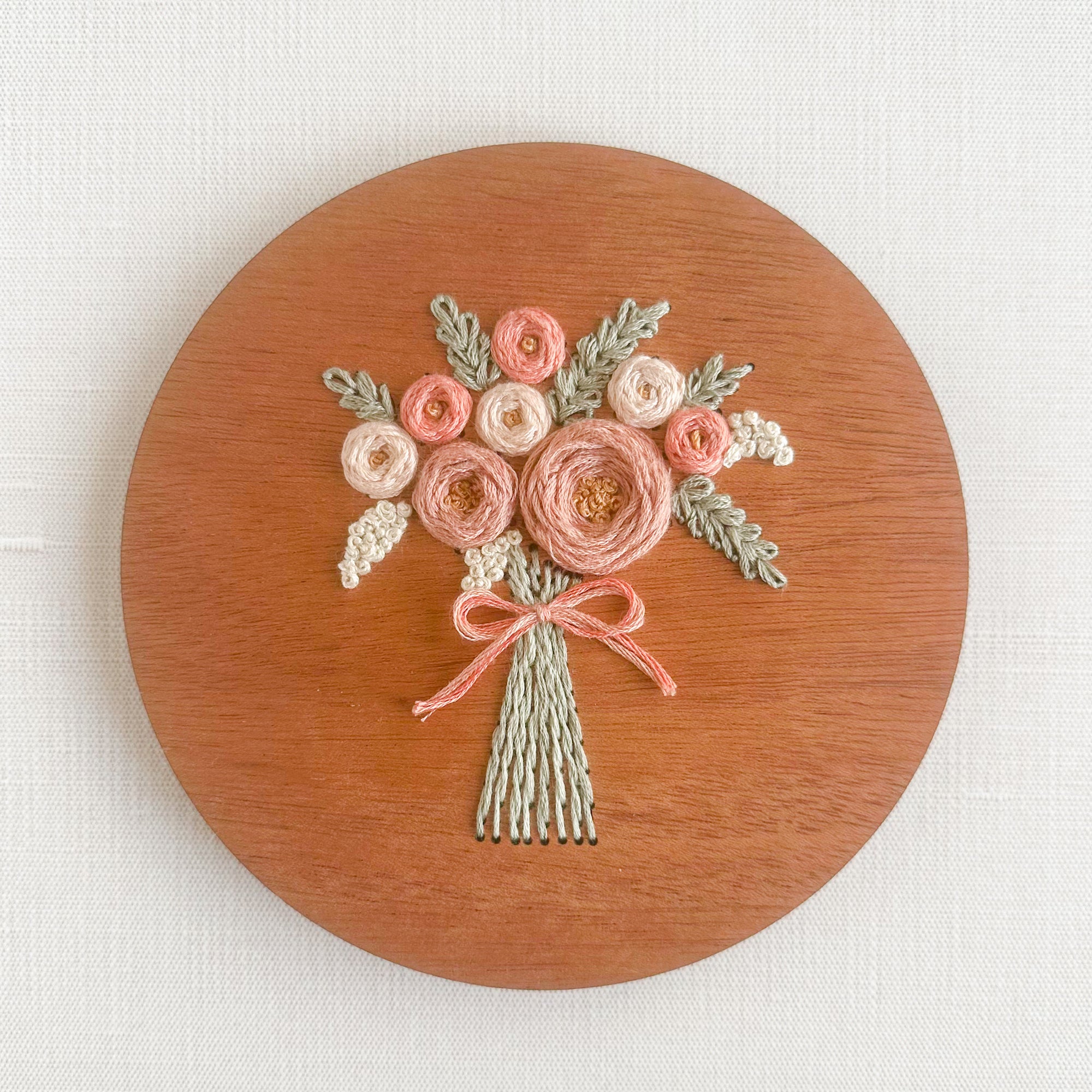 A sample of arose bouquet embroidery kit created with blush colored threads.